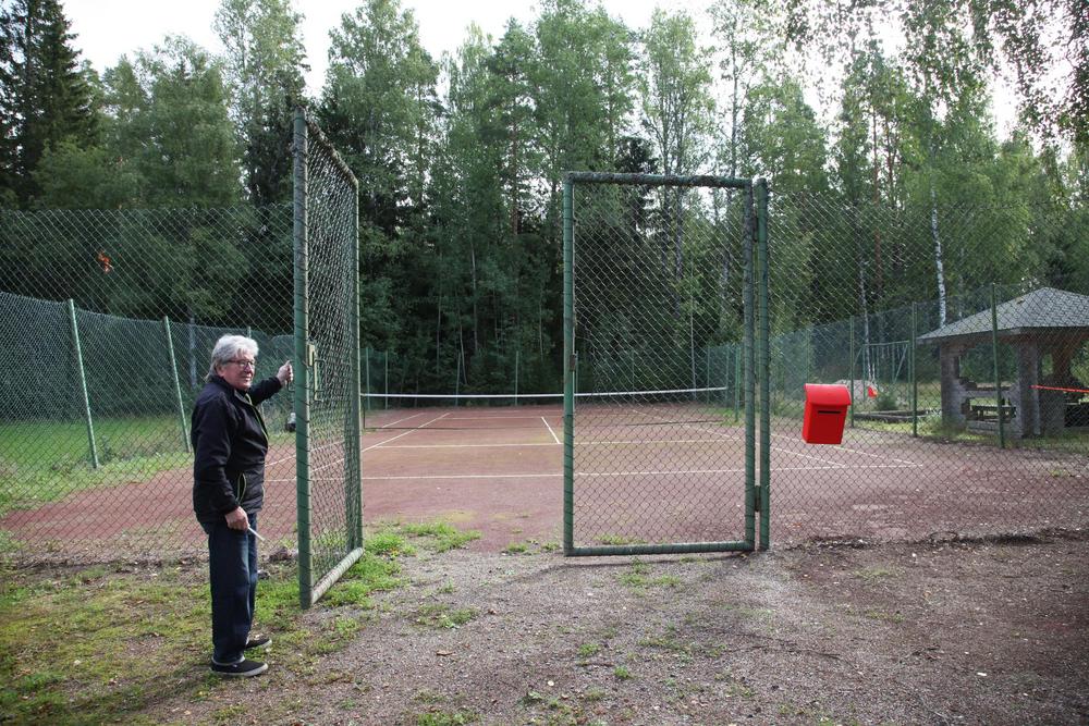 Kyläkeskuksen tenniskenttä — verkkoaita ja kentän portti auki